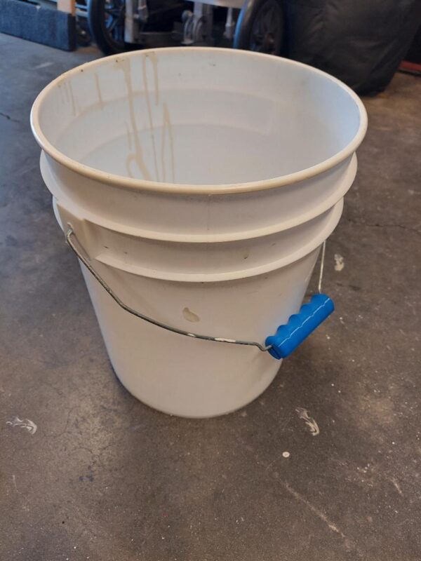 A white bucket with blue string attached to it.