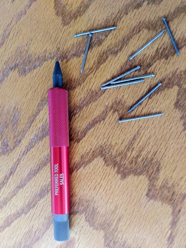 A red pen and some nails on the ground