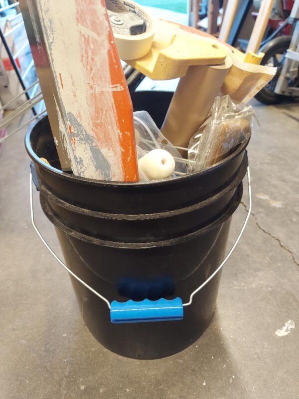 A bucket of construction supplies sitting on top of the floor.