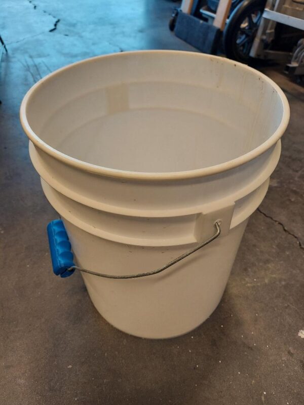 A white bucket sitting on top of the floor.