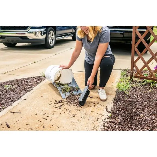 A woman kneeling down to pick up trash.