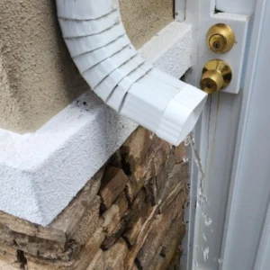 A white door with a gold handle and a brick wall