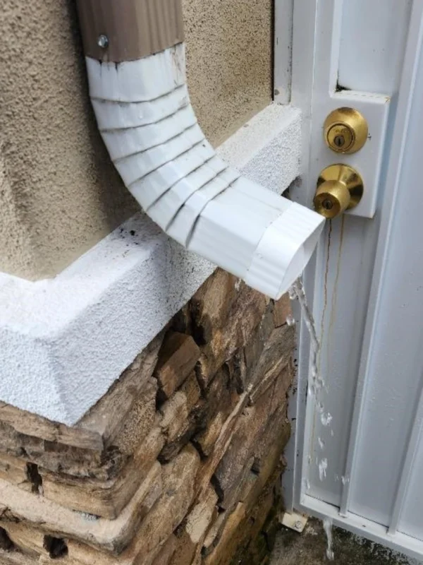 A white door with a gold handle and a brick wall