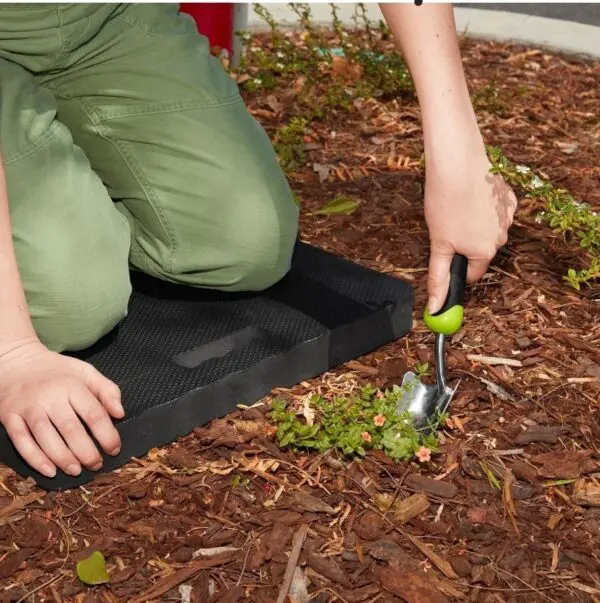 A person using a hammer to remove leaves from the ground.