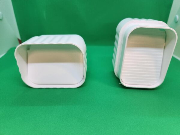 Two white plastic containers sitting on top of a green table.